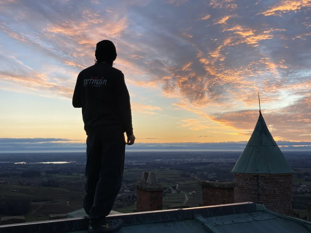 Couvreur sur un toit, regardant un coucher de soleil.