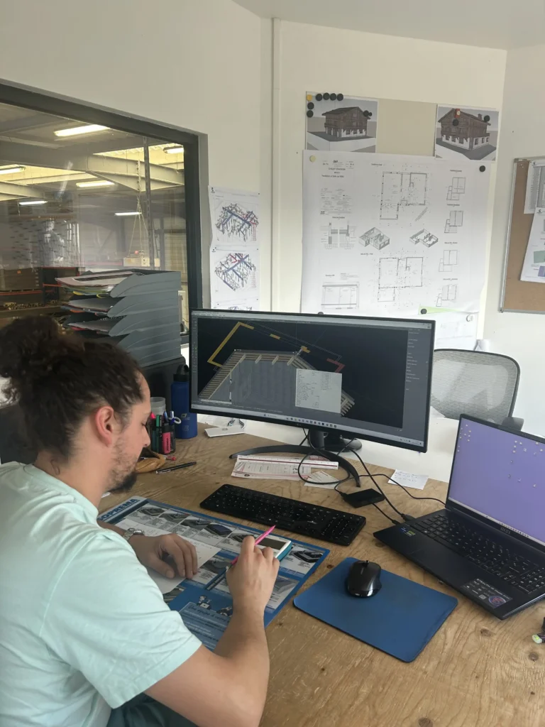 Ingénieur en conception travaillant sur des plans de construction dans un bureau d'étude avec des outils de conception assistée par ordinateur.