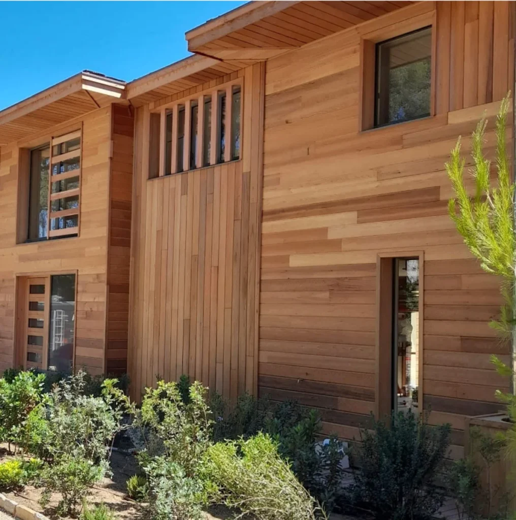 Façade d'une maison moderne en bois avec bardage et fenêtres.