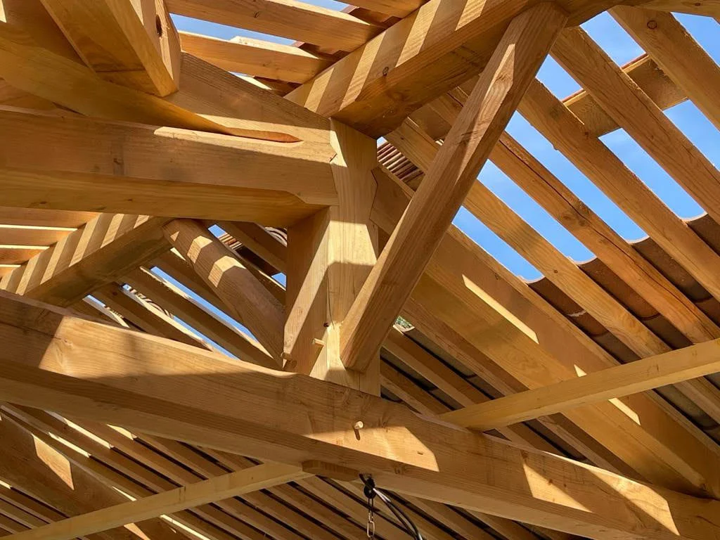 Charpente en bois massif sous un ciel ensoleillé.